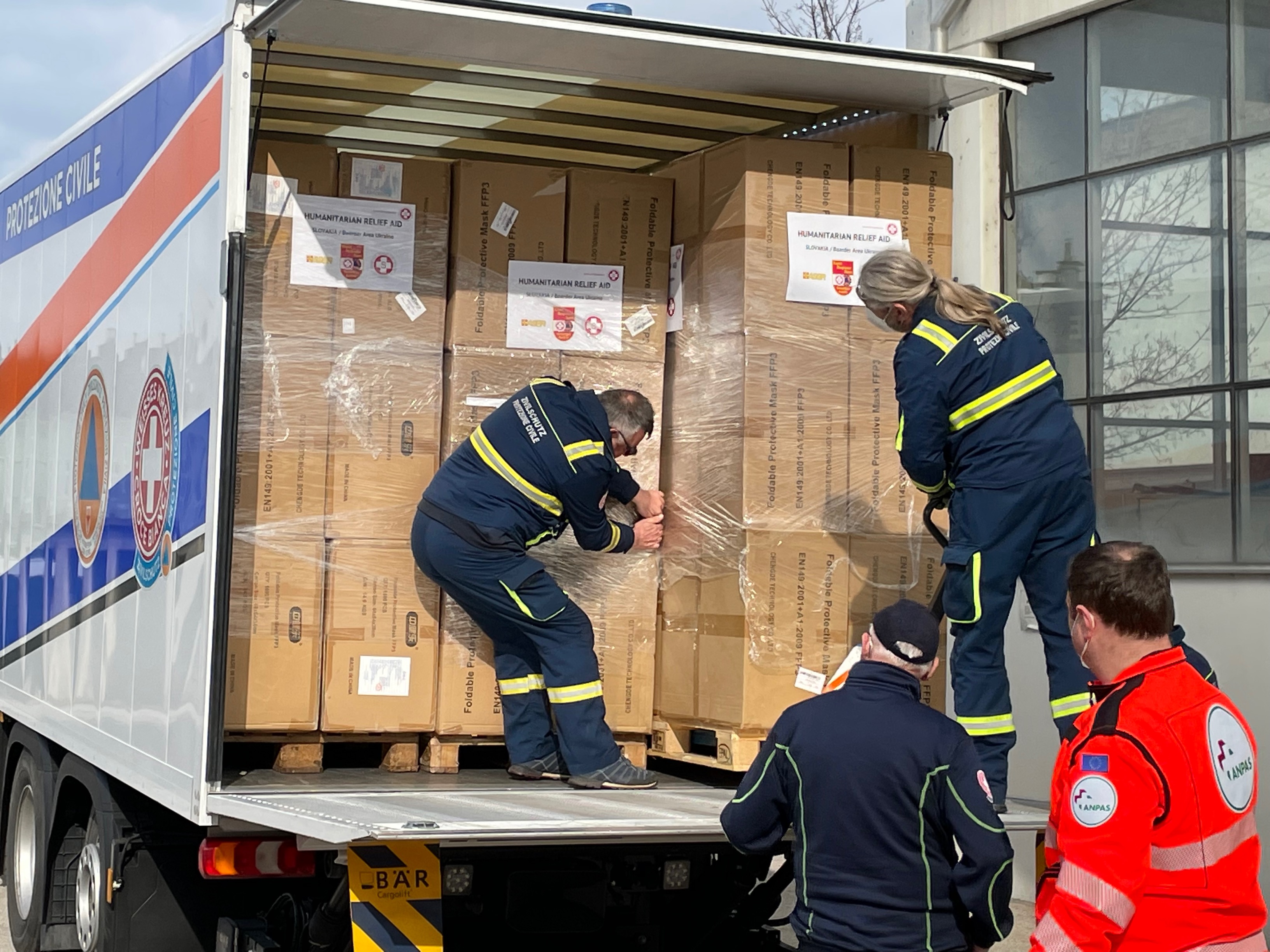 Vier Männer laden Paletten aus einem LKW aus.