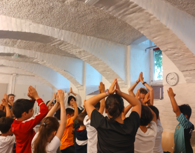 Mehrere Kinder klatschen gleichzeitig über ihrem Kopf.