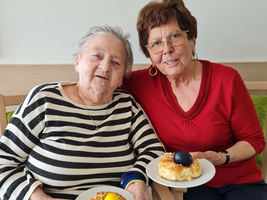 Zwei Frauen lächeln und halten Gebäck mit bunten Eiern in den Händen.