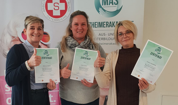 Drei Frauen halten stolz ihre Zertifikate und zeigen Daumen hoch.