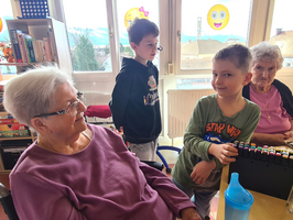 Kinder spielen mit Farben in einem Gemeinschaftsraum mit älteren Menschen.