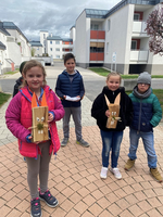 Kinder halten selbstgebastelte Figuren aus Holz in der Hand.