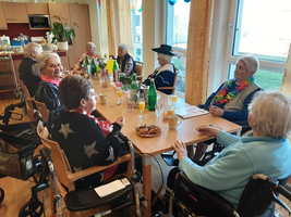 Ältere Frauen sitzen an einem Tisch und genießen Getränke und Snacks.
