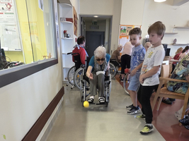 Eine ältere Person spielt mit Kindern Bowling mit bunten Kegeln.