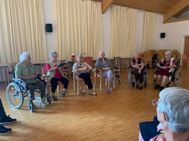 Ältere Frauen sitzen im Kreis und unterhalten sich in einem Gemeinschaftsraum.