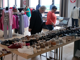 Eine Auswahl an Schuhen in einem Bekleidungsgeschäft mit Kunden.