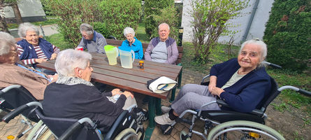 Ältere Menschen sitzen gemeinsam an einem Tisch im Freien.