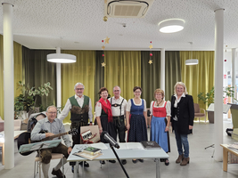 Gruppe von Menschen in traditioneller Tracht, die zusammen für ein Musikaufführung posieren.