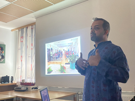Ein Mann spricht vor einer Präsentation über ein Klassenzimmer voller Schüler.