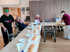 Gruppenaktivität mit älteren Menschen, die gemeinsam essen und sich unterhalten.