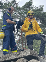 Zwei Rettungskräfte bei der Arbeit auf einem Trümmerfeld.