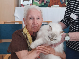Eine ältere Frau hält eine flauschige Katze in ihren Armen.