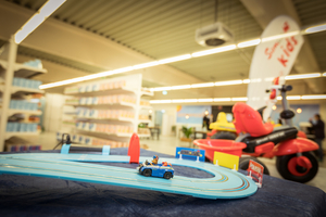 Ein blaues Spielzeugauto fährt auf einer Rennbahn in einem Spielwarenladen.