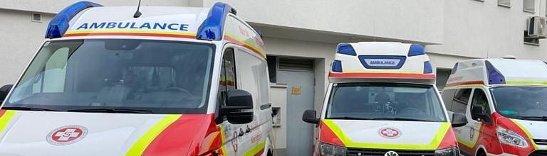 Drei Krankenwagen parken vor einem Gebäude.