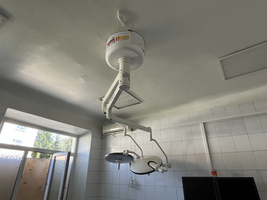 Operationsleuchte an der Decke eines weißen, gefliesten Raumes.