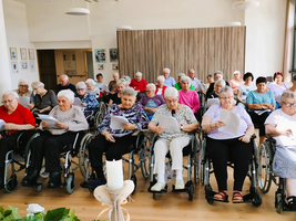 Eine Gruppe älterer Menschen sitzt in Rollstühlen und liest Texte.