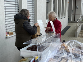 Zwei Frauen tauschen Süßigkeiten an einem Verkaufsstand aus.