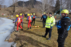 Rettungskräfte in Schutzanzügen bereiten sich auf eine Übung am zugefrorenen Gewässer vor.