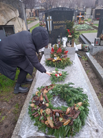 Eine Person legt eine Blumenschmuck auf ein Grab auf dem Friedhof.