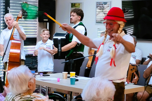 Eine fröhliche Musikdarbietung mit einem Clown in rotem Hut und Zöpfen.