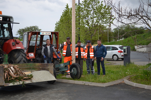 Fünf Männer stehen mit einem Traktor und Material in einem Parkplatz.