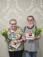 Zwei Frauen halten Blumensträuße und Dankeskarten in der Hand.