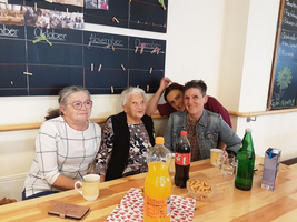 Vier Frauen sitzen an einem Tisch mit Getränken und Snacks.
