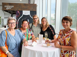 Fünf Frauen stehen an einem Stehtisch und unterhalten sich bei einer Veranstaltung.