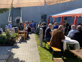 Eine Gruppe von Menschen sitzt im Freien unter einem Zelt.