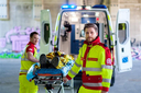 Zwei Sanitäter in Uniform transportieren eine Trage mit einer Person im Rettungswagen.