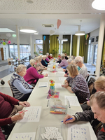 Senioren sitzen an einem Tisch und machen eine kreative Aktivität.