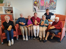 Eine Gruppe von sieben älteren Menschen hält frisch gebackenes Brot in der Hand.