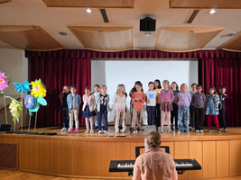 Eine Gruppe Kinder steht auf der Bühne und singt.