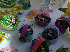 Bunte Osternester mit Schokoladeneiern und dekorativem Gras auf einem Tisch.