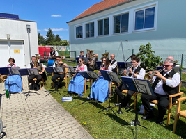 Eine Blaskapelle spielt im Freien, alle Musiker tragen traditionelle Trachten.
