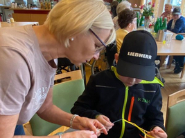 Eine Frau und ein Junge lernen gemeinsam, mit Fäden zu arbeiten.