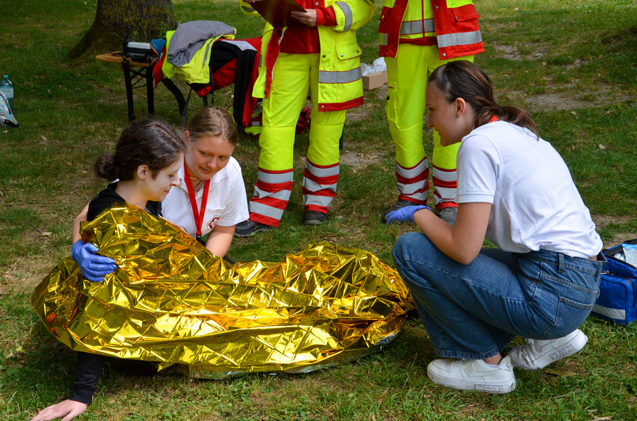 Zwei Helferinnen betreuen eine Person, die in eine Rettungsdecke eingewickelt ist.