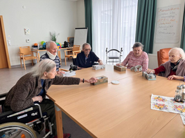 Ältere Menschen sitzen an einem Tisch und interagieren beim Spielen.