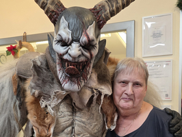 Eine Frau posiert neben einer gruseligen Figur mit Hörnern.
