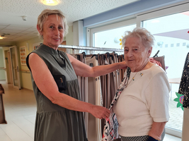 Zwei Damen probieren Bekleidung in einem hellen Raum an.