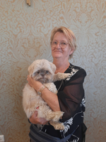 Eine Frau hält einen kleinen, flauschigen Hund in ihren Armen.
