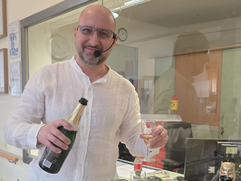 Mann serviert Sekt aus einer Flasche in Gläser.
