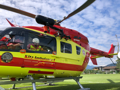 Ein farbiger Rettungshubschrauber steht auf einem grünen Sportfeld.