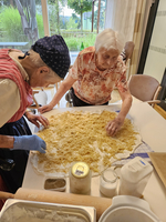 Zwei ältere Frauen bereiten gemeinsam einen Teig mit Kartoffelfüllung vor.