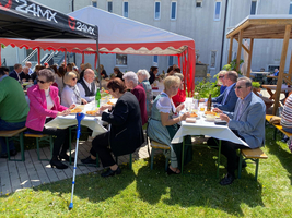 Senioren genießen ein gemeinsames Essen im Freien unter Zelten.