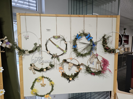 Eine Wand mit verschiedenen dekorativen Kränzen aus Pflanzen und buntem Zubehör.