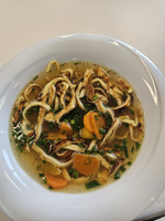 Eine Schüssel Suppe mit Nudeln, Möhren und frischem Schnittlauch.