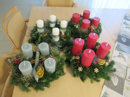 Zwei Adventskränze mit roten und grauen Kerzen, geschmückt mit Weihnachtsdeko.