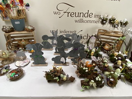 Dekorative Osternester und Hasenfiguren auf einem Tisch.