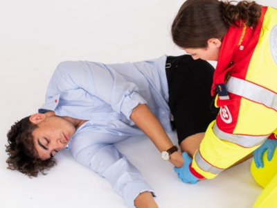 Ein Sanitäter behandelt einen verletzten jungen Mann am Boden.